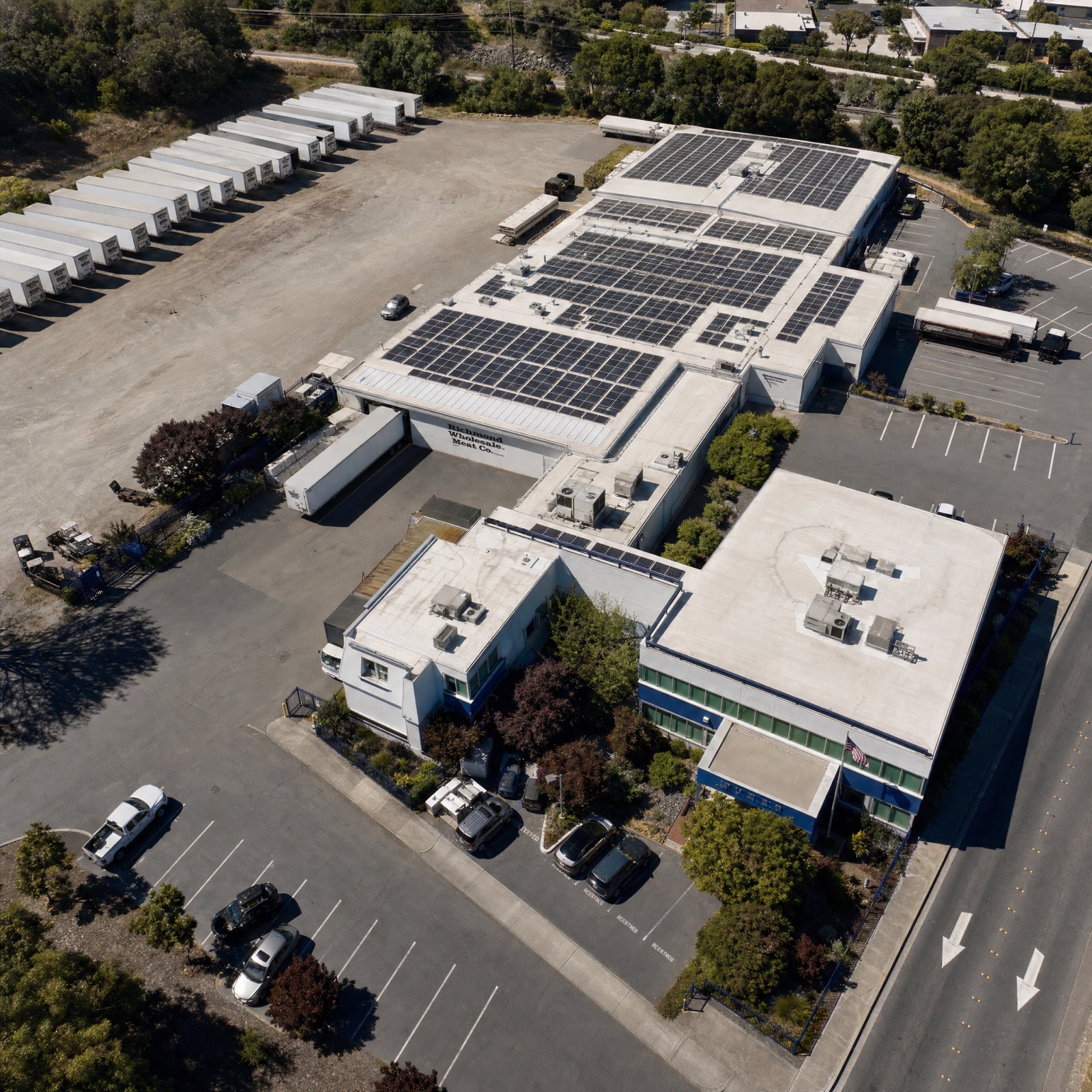 Rooftop solar over a refrigerated distribution warehouse with a row of reefer trailers